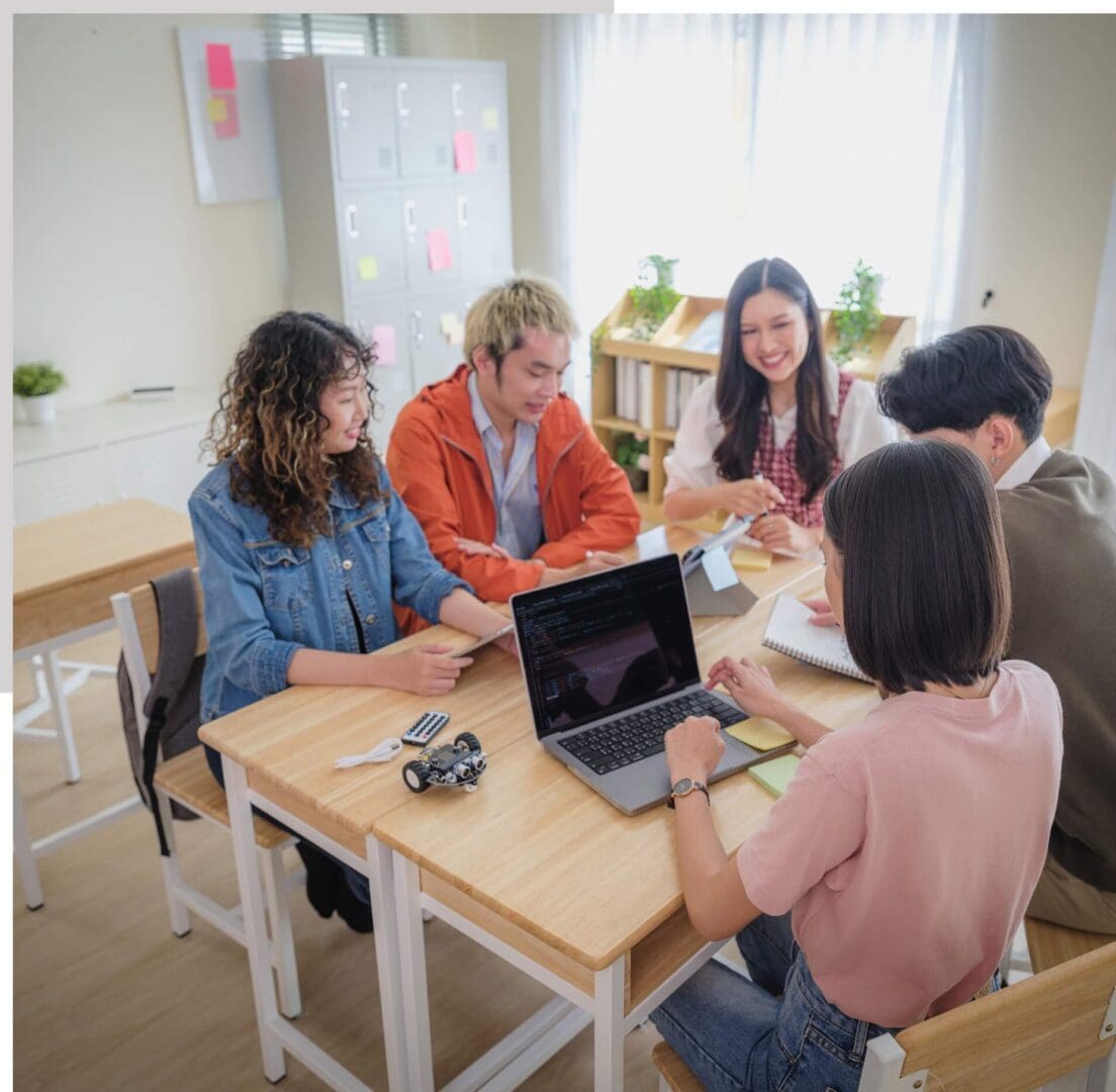 Four women collaborating around a laptop in a bright office space.